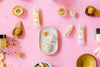 Fresh Pickins Farm products with flowers on a pink background