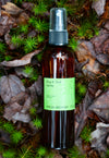 Fresh Pickins Farm Organic Bug & Tick Spray bottle in the maine forest