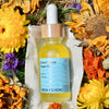 1oz Bottle of Beach Rose Face Oil by Fresh Pickins Farm in Maine surrounded by dried flowers.