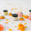 Jars of Fresh Pickins Farm organic body butter on a white surface with decorative flowers