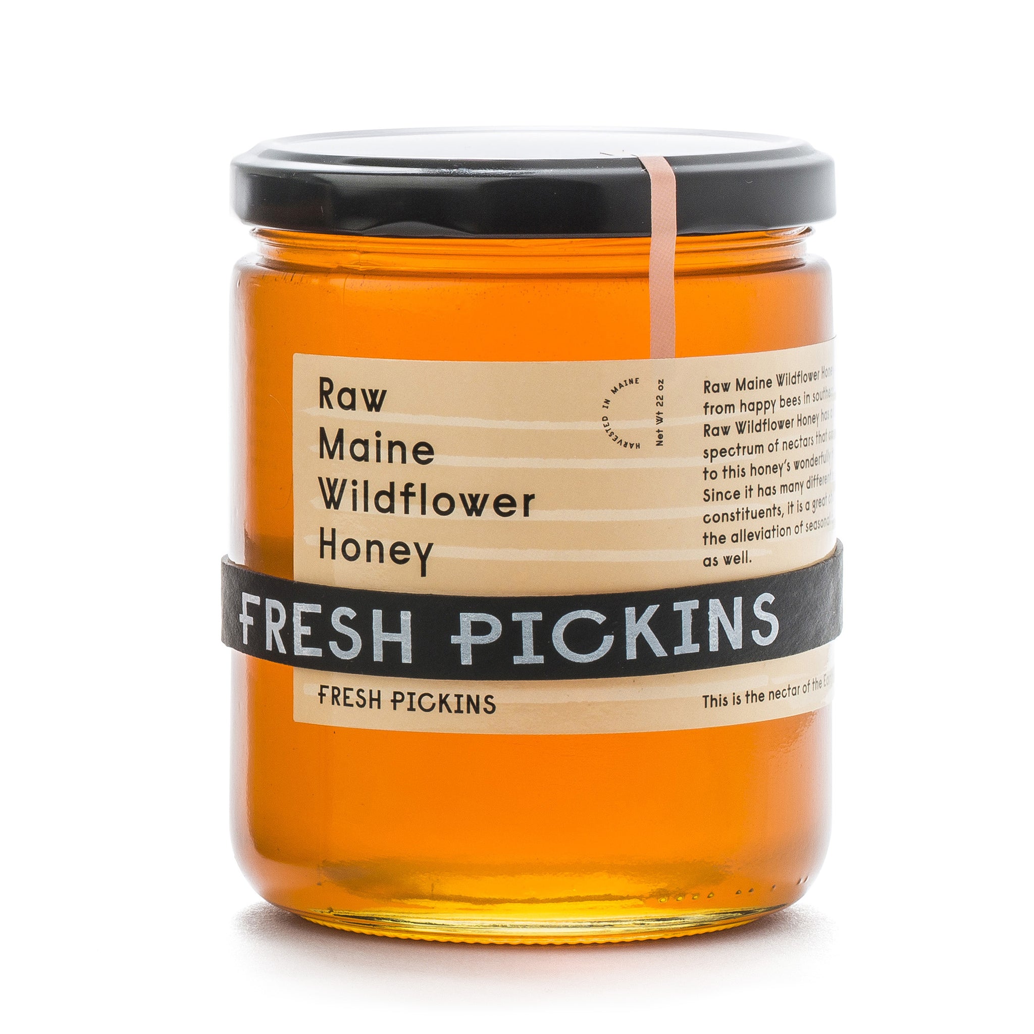 A jar of Fresh Pickins Farm  Raw Maine Wildflower Honey. The honey is visible through the clear glass jar and has a yellow color.